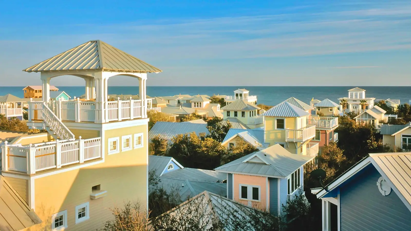 Pastel beach cottages with metal roofs and a rooftop tower overlooking the Gulf in Seaside, Florida.