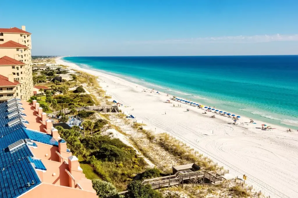 Aerial view of Miramar Beach, Florida with turquoise Gulf water, white sand, and beachfront resort buildings.