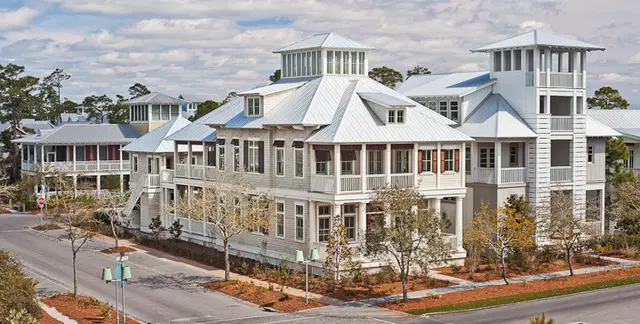 White coastal-style homes with metal roofs and wide porches along a landscaped street in WaterColor, Florida.